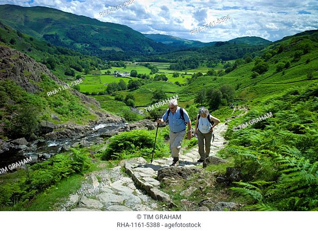 Tourists hill climbing on nature trail in lakeland countryside at Easedale in the Lake District National Park, Cumbria, UK