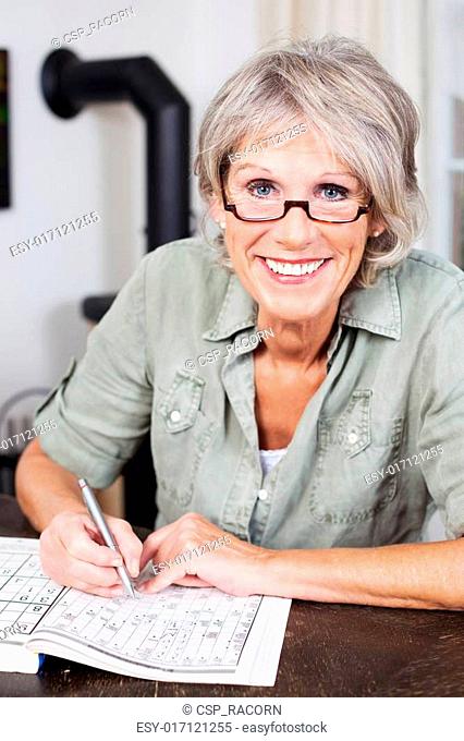 Smiling elderly woman doing a crossword puzzle