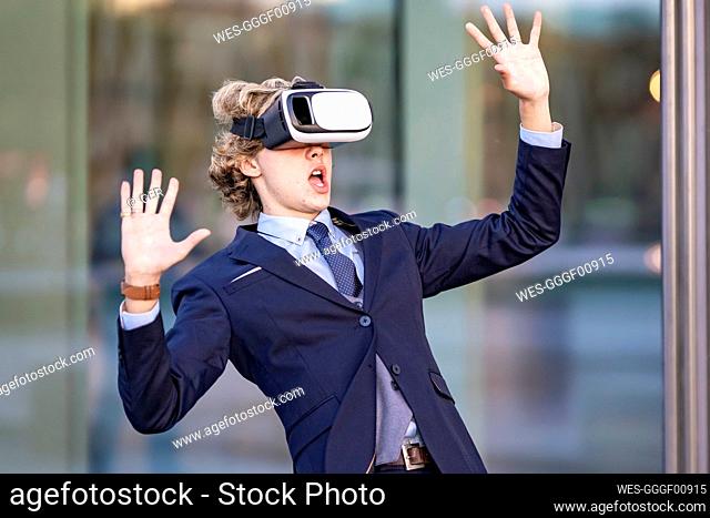 Businessman with mouth open wearing virtual reality simulator by glass wall