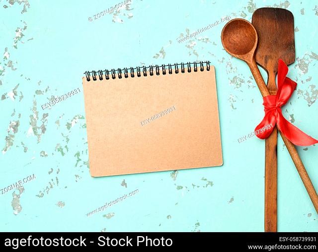 spoon and spatula tied with blue ribbon on green background, top view