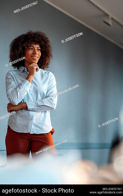 Businesswoman day dreaming with hand on chin at work place