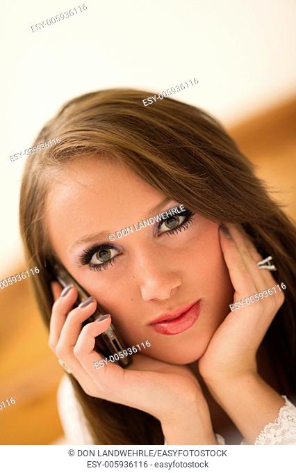 Teenage girl lying on a bed talking on a cell phone