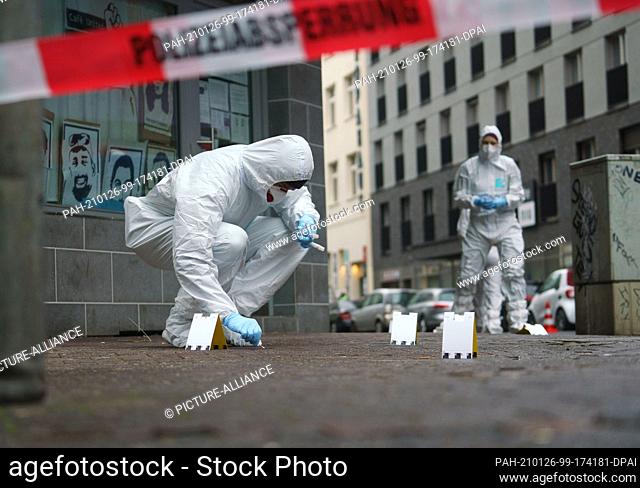 26 January 2021, Hessen, Frankfurt/Main: Officers of the forensics department secure traces of blood on the sidewalk in Niddastraße