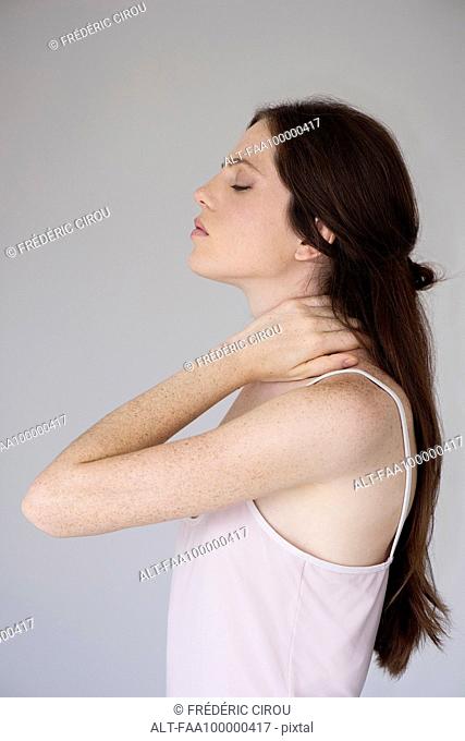 Woman rubbing neck, side view