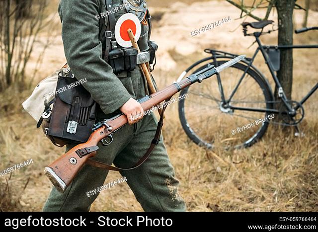 Re-enactor Dressed As World War II German Soldier Feldgendarm Gendarme Holding Rifle. Soldier Holding Weapon. German Military Ammunition Of A German WW2 Soldier