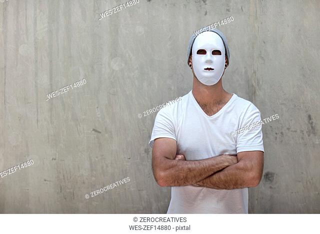 Man wearing a mask standing next to a concrete wall