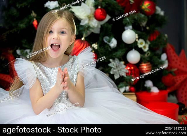 Beautiful child with a christmas gift. Dressing up girl at the New Year tree