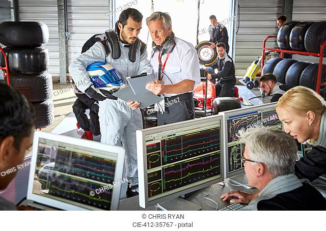 Manager and formula one driver discussing telemetry diagnostics in repair garage