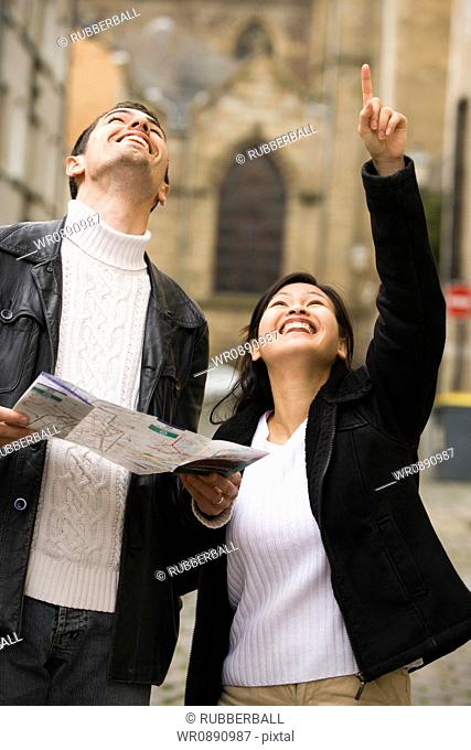 Close-up of a young couple holding a map and looking up