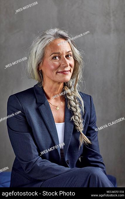 Smiling female professional in business casual against gray wall