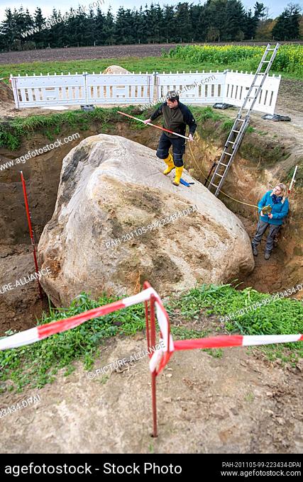 05 November 2020, Lower Saxony, Hüven: The geologists Janine Meinsen (l) and Roberto Pierau examine a huge erratic block