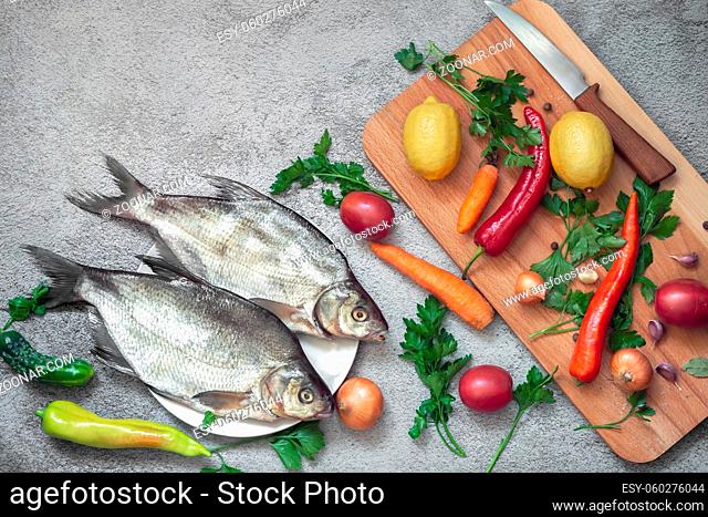 On the plate are two large bream. Nearby are vegetables and spices for cooking this river fish. Top view with copy space. Flat lay