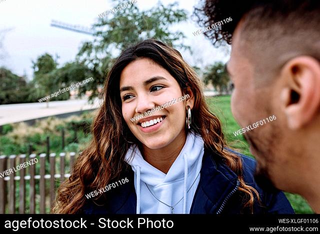 Smiling teenage girl with male friend at public park