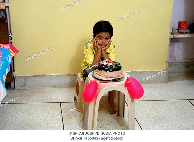 Young boy looking at birthday cake in house MR704