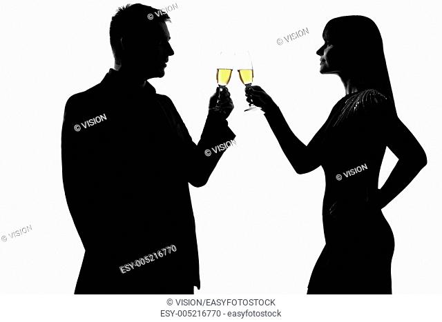 one caucasian couple man and woman drinking champagne toasting partying in studio silhouette isolated on white background