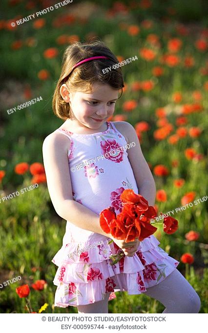 Little girl in a poppy field holding a bouquet