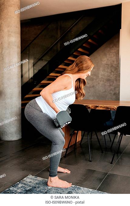 Pregnant woman using weights at home