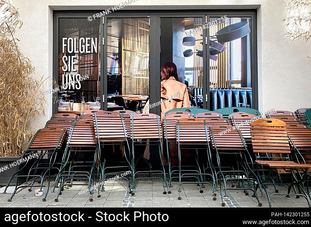 Topic picture: Coronavirus pandemic / consequences for gastronomy: Chairs and tables stacked on top of each other are leaning against the wall of a restaurant...
