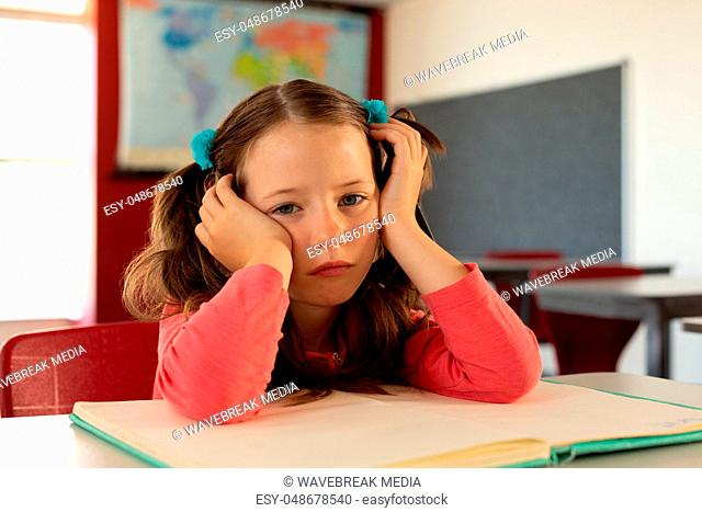 Sad girl leaning on desk in a classroom