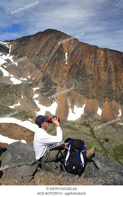 Hiker taking break on trail up to peak of Hudson Bay Mountain, Smithers, British Columbia