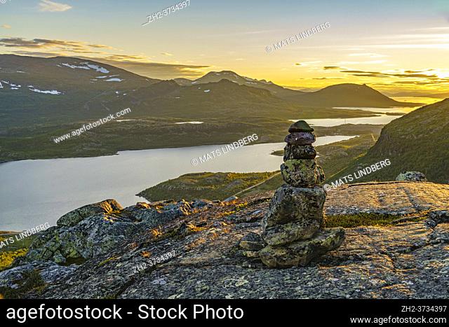 View over Stora sjöfallet nationalpark in the evening with nice warm evening light, mountains in background, heap of stones in foreground