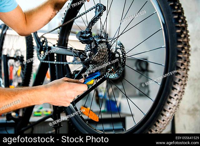 Bicycle repair in workshop, man setting up cassette closeup. Mechanic in uniform fix problems with cycle, professional bike repairing service
