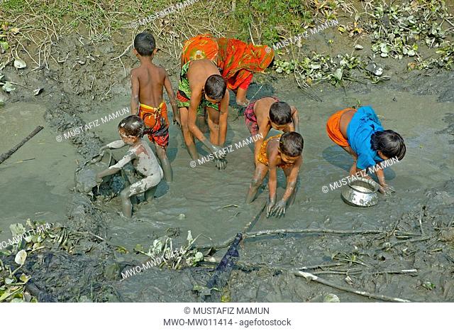 Woman and children catching fishes in a muddied pond Singair, Manikganj, Bangladesh December 25, 2007