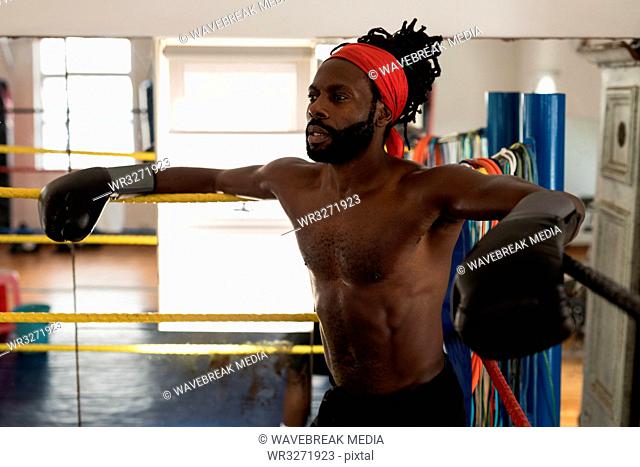 Male boxer relaxing in boxing ring at fitness studio