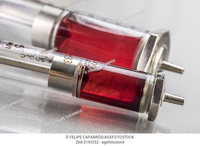 Two vintage syringes with red medication, conceptual image