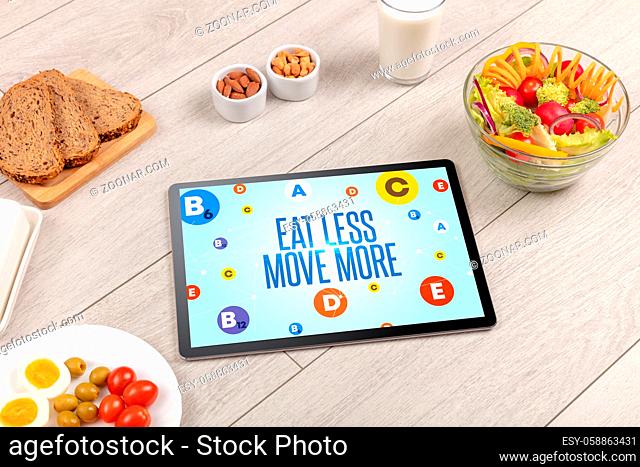 Healthy Tablet Pc compostion with EAT LESS MOVE MORE inscription, weight loss concept