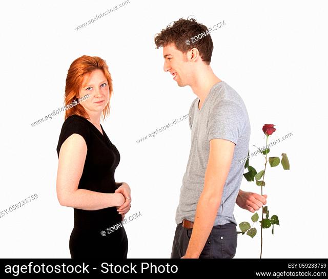 Passionate man hidden a rose behind his back for his girlfriend; isolated on white