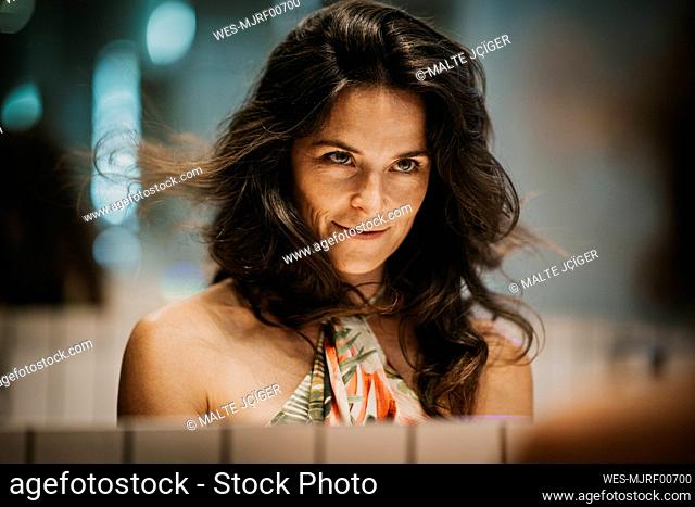 Woman with long hair looking at reflection in mirror