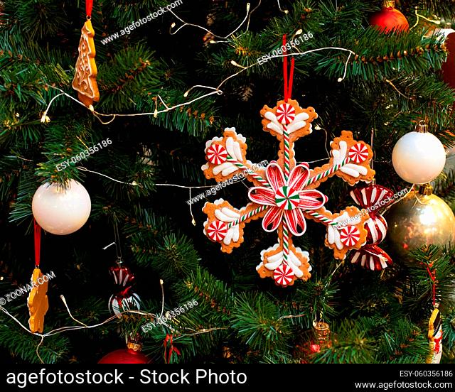 A large snowflake cookie decorated with sweet sugar icing. Christmas tree decorated with ginger sweets, cookies and balls