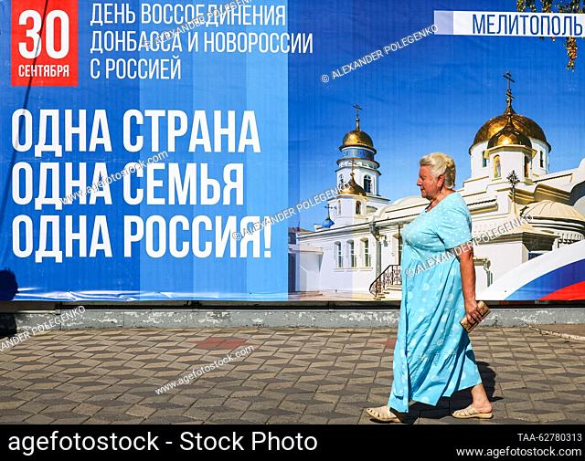 RUSSIA, MELITOPOL - SEPTEMBER 29, 2023: A woman walks past a banner celebrating the reunification of Russia, Donbass and Novorossia