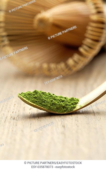 Japanese bamboo matcha spoon, chashaku, with green tea and chasen on the background