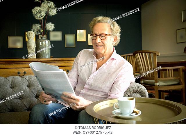 Smiling senior man in lounge room reading magazine