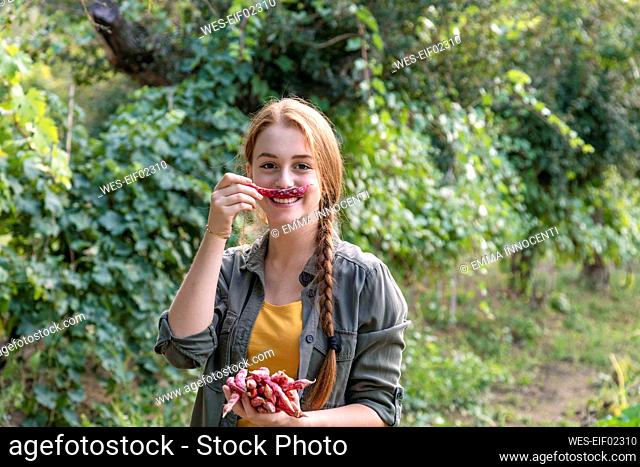 Playful female farmer holding bean in front of mouth