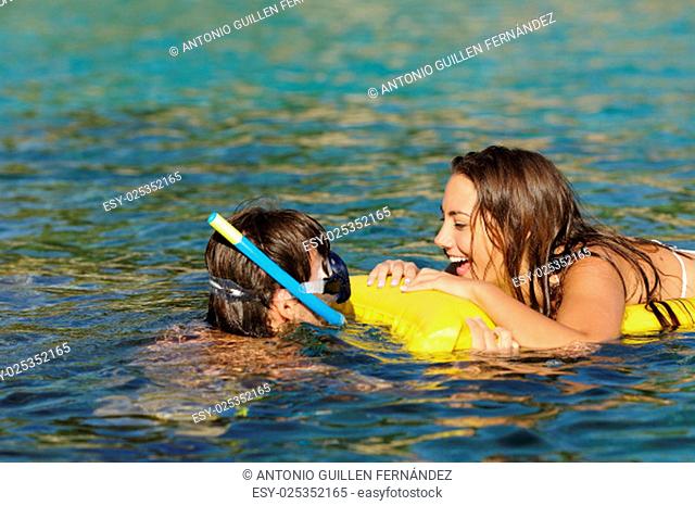Couple of tourists laughing while bathing on a tropical beach with turquoise water on summer vacations