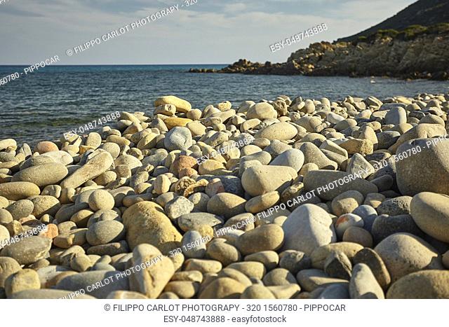 Detail of some white pebbles on a typical beach of the southern coast of southern Sardinia in Italy, with the background of the rest of the beach and the sea