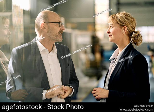 Businessman and businesswoman talking in a factory