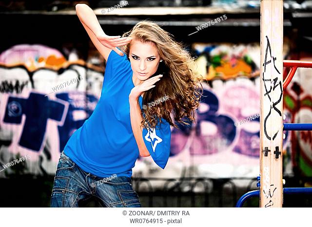 Young beautiful girl at the street with graffiti wall