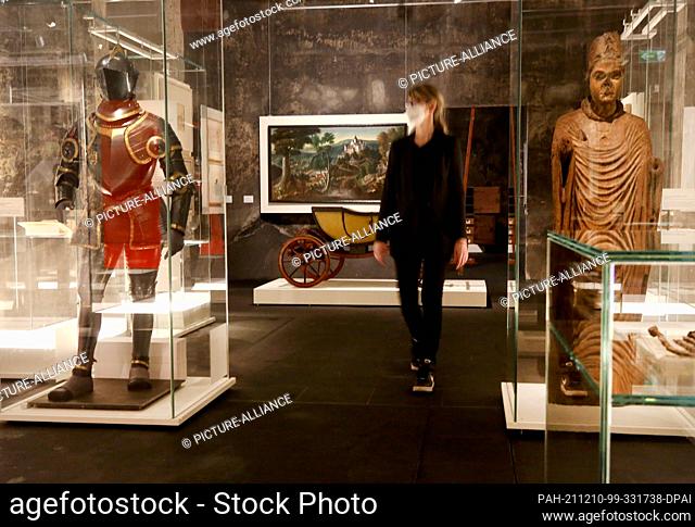 10 December 2021, North Rhine-Westphalia, Essen: A trade visitor looks at the magnificent armour of Duke Wilhelm V of Jülich-Kleve-Berg (1555) and the statue of...