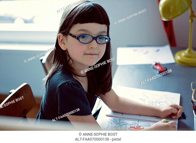 Girl sitting at desk with coloring book