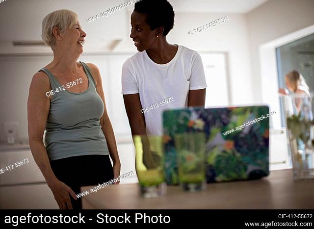 Happy senior women friends exercising at laptop in dining room