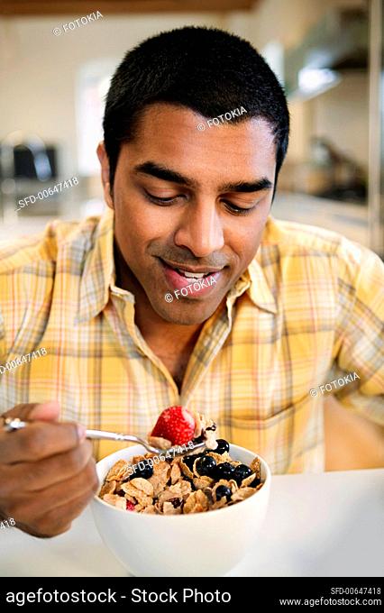 A Man Eating a Bowl of Bran Flake Cereal with Fresh Berries