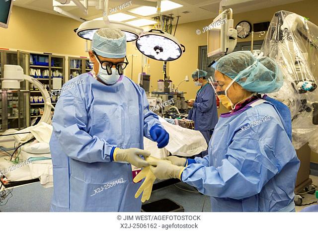 Englewood, Colorado - A nurse helps Dr. Paul Elliott prepare to perform lumbar spine surgery on a patient at Swedish Medical Center