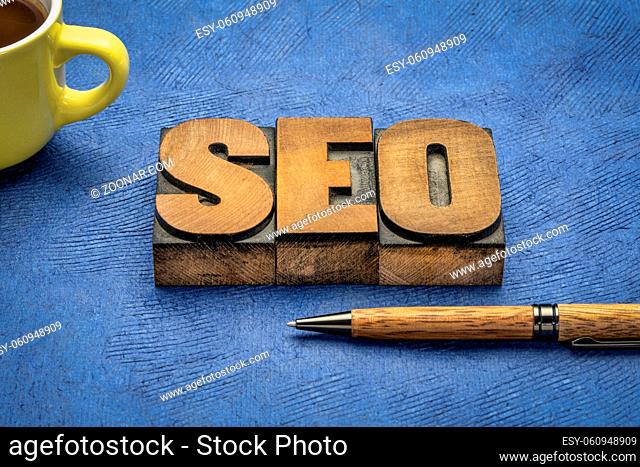 search engine optimization (SEO) - acronym in vintage letterpress wood type printing with a pen and coffee, internet and web design concept