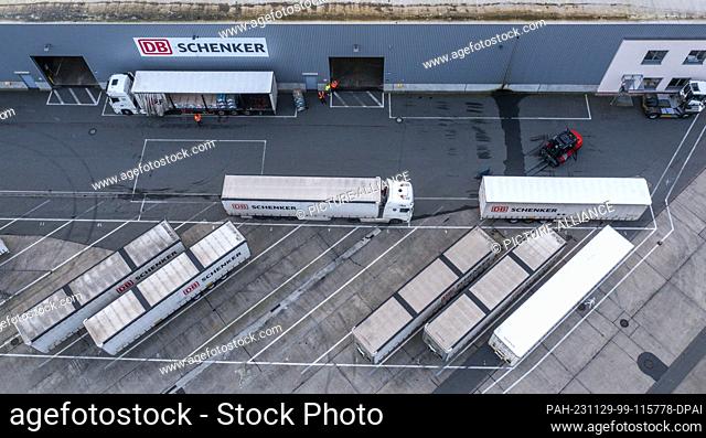 PRODUCTION - 21 November 2023, Mecklenburg-Western Pomerania, Rostock: Trucks of the logistics company DB Schenker are unloaded on the premises of the logistics...