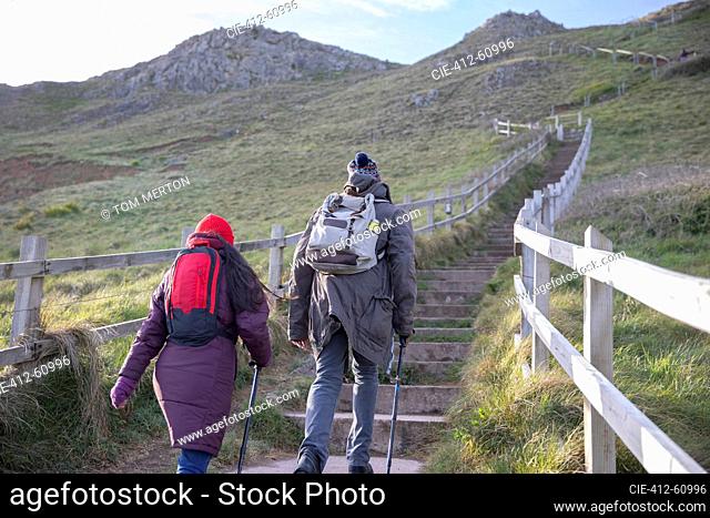 Couple with backpacks hiking up stairs on cliff