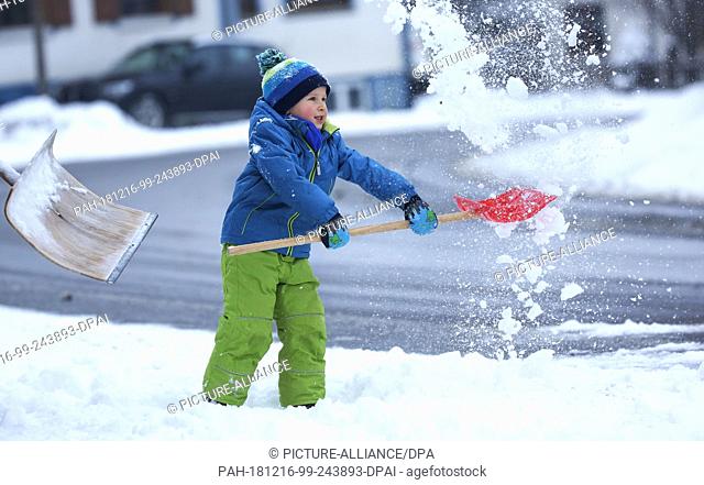 16 December 2018, Baden-Wuerttemberg, Langenenslingen-Ittenhausen: Gabriel throws snow into the air with a snow shovel. In the morning it snowed on the Swabian...